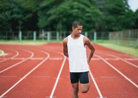 Athletes sport man runner wearing white sportswear to stretching and warm up before practicing on a running track at a stadium. Runner sport concept. photo