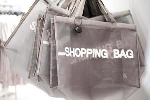 Group of the shopping bags hanging on the rack waiting for the buyer to use in the store. Selective focus on the letter S of Shopping bag. photo