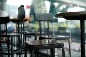 Closeup modern style of wooden chair on the metal structure in the coffee shop with blurred inside cafe in background photo