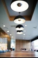 Closeup the edge of wooden table in the cafe with blurred background of modern interior design room and lighting lamp photo