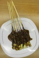 Sate or satay with peanut sauce and cucumber on a plate photo