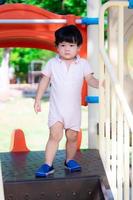 Handsome boy is standing in sun at playground under shadow of toys. Child is sweating under nose. During summer or spring time. Health care for young kid concept. Baby aged 2 years old. photo