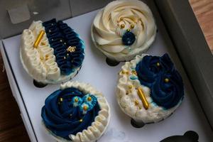 Luxurious and elegant cupcakes, with white cream and navy blue with gold sprinkles. photo