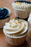 Luxurious and elegant cupcakes, with white cream and navy blue with gold sprinkles. photo