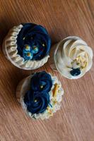 Luxurious and elegant cupcakes, with white cream and navy blue with gold sprinkles. photo