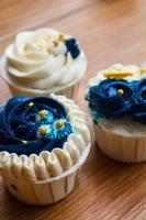 Luxurious and elegant cupcakes, with white cream and navy blue with gold sprinkles. photo