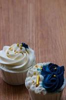cupcakes lujosos y elegantes, con crema blanca y azul marino con chispas doradas. foto