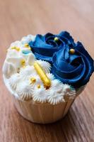 cupcakes lujosos y elegantes, con crema blanca y azul marino con chispas doradas. foto