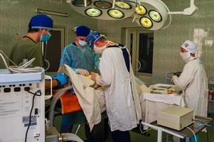 VINNITSA UKRAINE OCTOBER 25 of 2022 A horizontal skilled surgeons and a watchful nurse performing an operation under the bright electric lamp in a modern operation center in hospital in Vinnitsa. photo