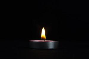 A Close-up of lighting candle with yellow flame, a Light of candle in the dark, it burns and after a while a gust of wind extinguishes it. photo