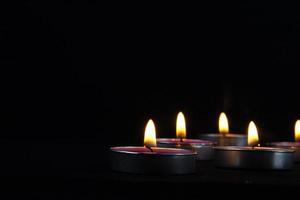 A Close-up of lighting candle with yellow flame, a Light of candle in the dark, it burns and after a while a gust of wind extinguishes it. photo