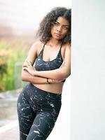 Young woman standing, confident looking, portrait. A beautiful African American person has attractive curly afro hair. Modern multi-ethnic girl enjoy carefree relaxing outside with cool posing photo