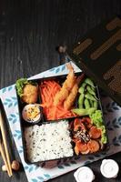 Caja bento japonesa con salchicha, nugget, huevo y gamba tempura foto