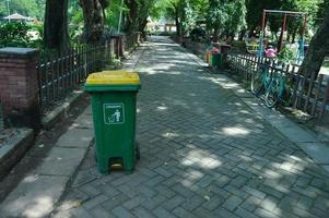 a road in a park with a green trash can by the side of the road photo