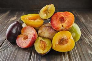 Fresh ripe plums of three colors whole and half on wooden background photo