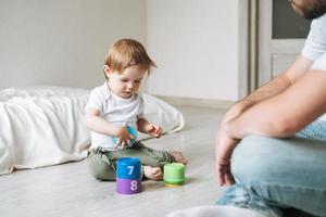 Happy father young man and baby girl little daughter having fun playing with toy in children room at home photo