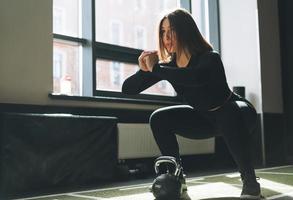 Young woman training her muscles with kettlebell in fitness club gym photo