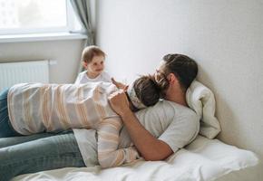 joven familia feliz con una niña en la cama en casa foto