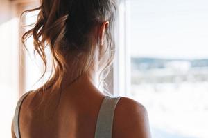 foto de primer plano de una joven mujer rubia de fitness esbelta desde atrás cerca de la ventana de casa