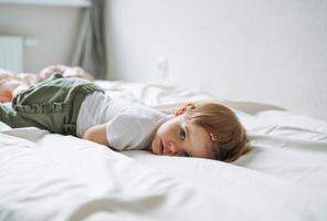 linda y divertida niña vestida de casa yace en la cama en casa foto