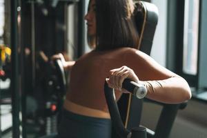 joven mujer morena fitness entrenando para equipos de músculos de la mano en el gimnasio, enfoque selectivo foto