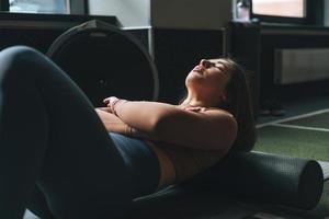 joven morena haciendo pilates de estiramiento en rollo de masaje en el gimnasio del club de fitness foto