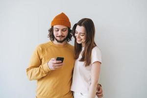 Couple young family hipsters using mobile phones on gray wall background photo