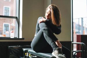 retrato de una joven morena descansando con ropa deportiva activa en el gimnasio foto