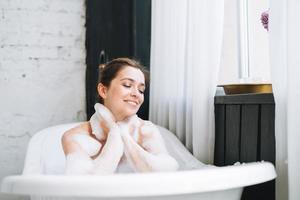 joven mujer feliz bañándose con espuma en casa, date un capricho foto