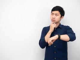 el hombre asiático muestra su reloj sintiendo vacilación mirando el espacio de la copia fondo blanco foto