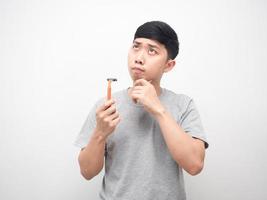 Asian man holding shaving gesture thinking and looking up for choose shaving photo