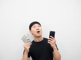 Man holding money and mobile phone feeling excited looking above photo