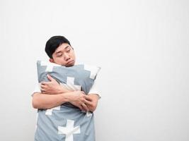Asian man hug pillow feeling sleepy look at space white background photo