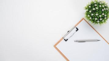 Pen on document board and vase on the table top view copy space white background photo