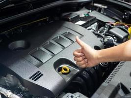 Hand thumb up with the engine of new car photo