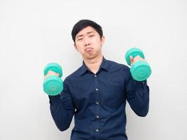 Asian man holding dumbbell feeling lazy to workout photo