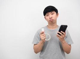 hombre sujetando el cable cargando el móvil con el smartphone aburrido emoción espacio de copia foto