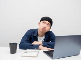 Man sit at the desk with laptop feeling bored looking up at copy space photo