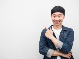 hombre asiático camisa de jeans gesto sonriente apuntando con el dedo al espacio de copia foto