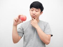 hombre mirando una manzana roja en la mano pensando en el fondo blanco de la atención médica foto