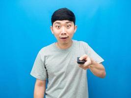 Asian man gesture press remote control television blue background photo