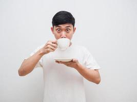 hombre camisa blanca se siente asombrado con beber café en la mano mira la cámara sobre fondo blanco foto