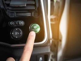 Finger at energy save mode button of eco car with light flare photo