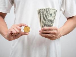 primer plano hombre camisa blanca muestra golden bitcoin y dinero dólar en su mano foto