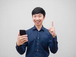 Asian man cheeful happy smile holding mobile phone and point finger get idea concept on white background photo