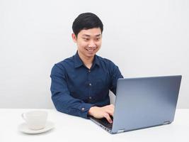 hombre asiático que usa una computadora portátil en la mesa para trabajar en casa foto