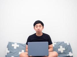 Man with laptop sitting on the bed feeling tried and want to sleep photo