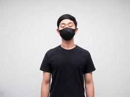 Asian young man black shirt with mask close his eyes feel sleepy on white isolated background photo