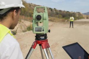 Surveyor engineer is measuring level on construction site. Surveyors ensure precise measurements before undertaking large construction projects. photo