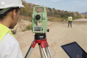 Surveyor engineer is measuring level on construction site. Surveyors ensure precise measurements before undertaking large construction projects. photo